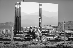 Photograph of workers walking by a heliostat trailer, Unit 1 solar field, June 4, 2012