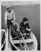 Rex Bell (George Francis Beldam)(seated) on a small skiff boat with two other unidentified people at an unknown location