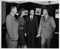 Rex Bell (George Francis Beldam) with Premier Manning, Joan Adams and Provincial Secretary Patrick at an unknown location. Stamped on back: Credit Please, Credit line should be used when this photograph is published.  Ernst of Goertz