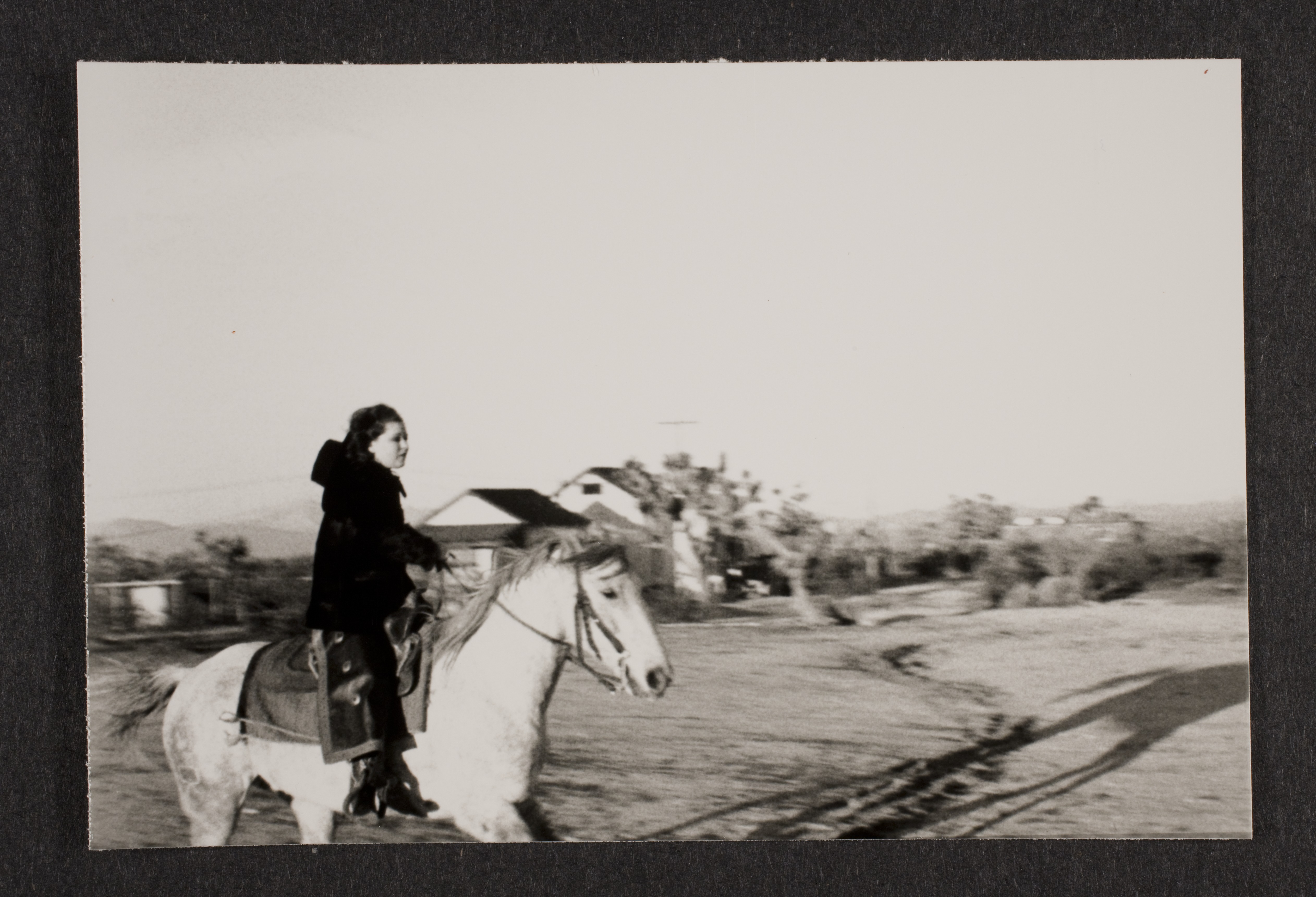 Clara Bow on a horse at Walking Box Ranch, Nevada riding past guest house: photographic print