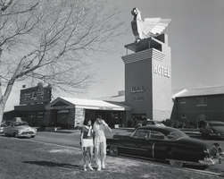 Photograph of a couple posing near the front entrance of the Thunderbird Hotel, Las Vegas, circa 1950s