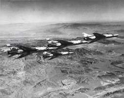 Black-and-white photograph of F-100 fighter aircrafts over Nellis Air Force Base, Nevada, circa mid 1950s