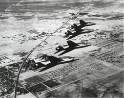 Black-and-white photograph of F-100A fighter aircraft in flight, Nellis Air Force Base, Las Vegas, circa 1950s