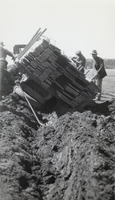 Photograph of men and a truck carrying wooden planks, circa 1920s to 1930s