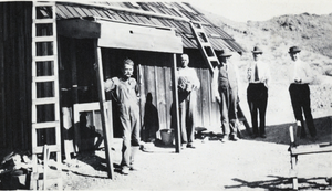 Photograph of men beside building, circa 1920s-1940s