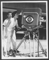 Black-and-white photograph of Toni Clark taking a peek into a CBS TV camera at Wilbur Clark's home, Las Vegas, Nevada, 1957