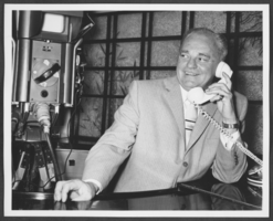 Black-and-white photograph of Wilbur Clark answering the telephone at his home in Las Vegas, Nevada, 1957