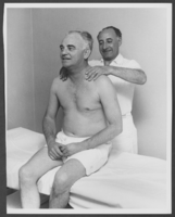 Black-and-white photograph of Wilbur Clark receiving a massage, location unknown, circa 1950s