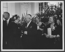 Black-and-white photograph of Russian Premier Nikita Khrushchev and his wife Nina Khrushcheva at a reception, location unknown, 1959