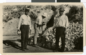 Photograph of three men near a rock pile, circa early 1900s