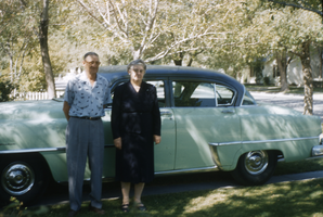 Slide of Earl Hubbard and a woman in front of a car, circa 1955