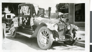 Photograph of a car decorated with politcal signs, 1930