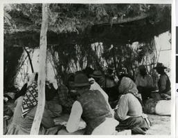 Photograph of a gathering of Piautes gambling under shade shelter, Pahrump Valley, Nevada, circa 1890s-1910s