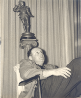 Photograph of Jay Sarno seated with statue behind him, 1960s