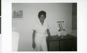 Photograph of Dorothy Collins posing next to a campaign poster promoting Rev. Leo Johnson for City or County commission