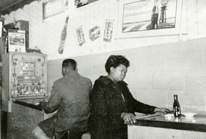 Photograph of "Kitty" playing a pinball machine at Jimmy Snowden Liquor Store