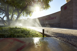 Sprinklers watering grass in common area of the Summerlin village of The Willows, Las Vegas, Nevada: digital photograph