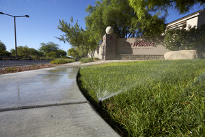 Sprinklers watering grass in common area of the Summerlin village of The Willows, Las Vegas, Nevada: digital photograph