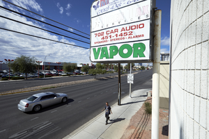 A man walking on a sidewalk beneath a sign on East Sahara Avenue looking southwest, Las Vegas, Nevada: digital photograph