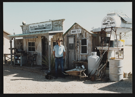 Phil Benson standing in front of his newspaper office: photographic print