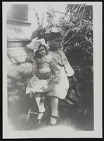 Nanelia Siegfried holding a doll outside a house: photographic print