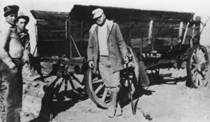John Quincy Lisle standing beside an ore wagon intended for use in a sodium sulphate mine, Moapa Valley: photographic print