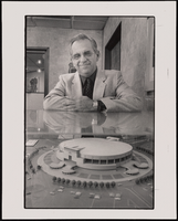 Arturo Cambeiro, architect, stands looking down at a model of the Thomas & Mack Center, which he designed: black-and-white photographs