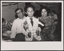 Carmelita and Leopoldo Galban with grandson, Shaun, attending the first social event of the Las Vegas Nicaraguan Association of Las Vegas. Shaun is holding an American flag in his right hand, and a Nicaraguan in his left: black-and-white photographs