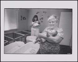 Hope Lezcano stands with another woman holding infants in her group nursey, Tender Loving Care, which cares for newborn infants up to age two in Las Vegas, Nevada: black-and-white photographs