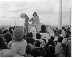 Photograph of a parade float carrying a costumed person and a beauty queen