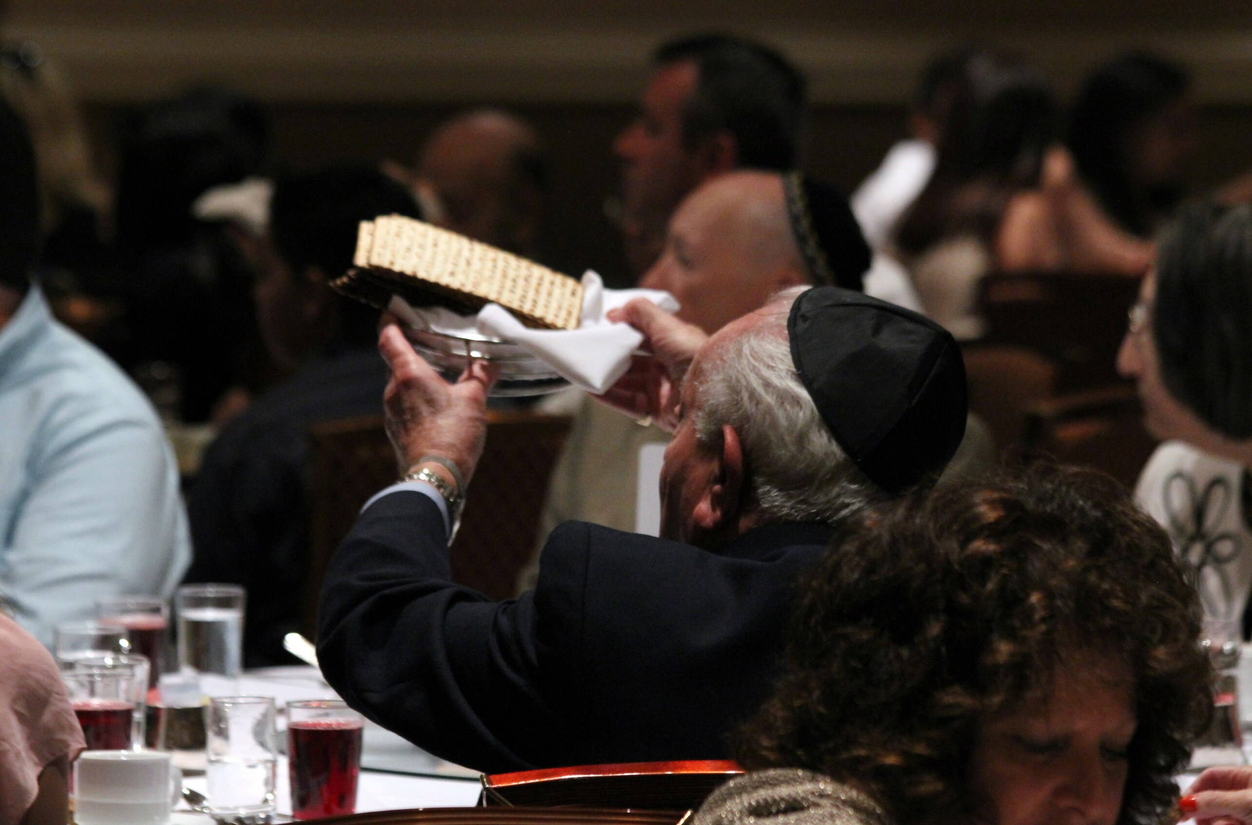 Holocaust survivor holds up matzo (photo by Jordan Kyle Hoffman)