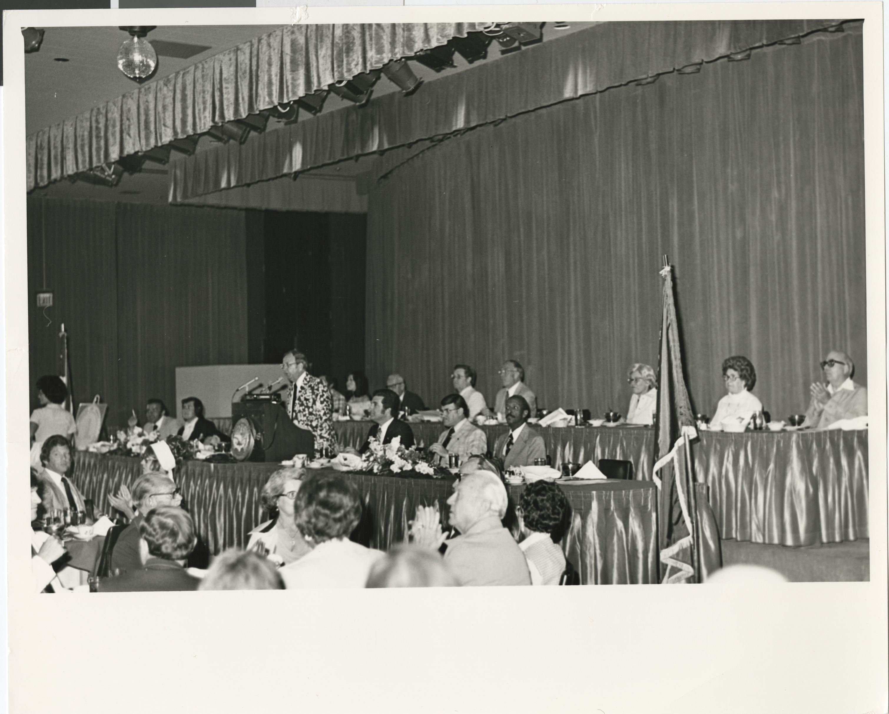 Photograph of Ron Lurie at a conference presentation (seated next to podium)
