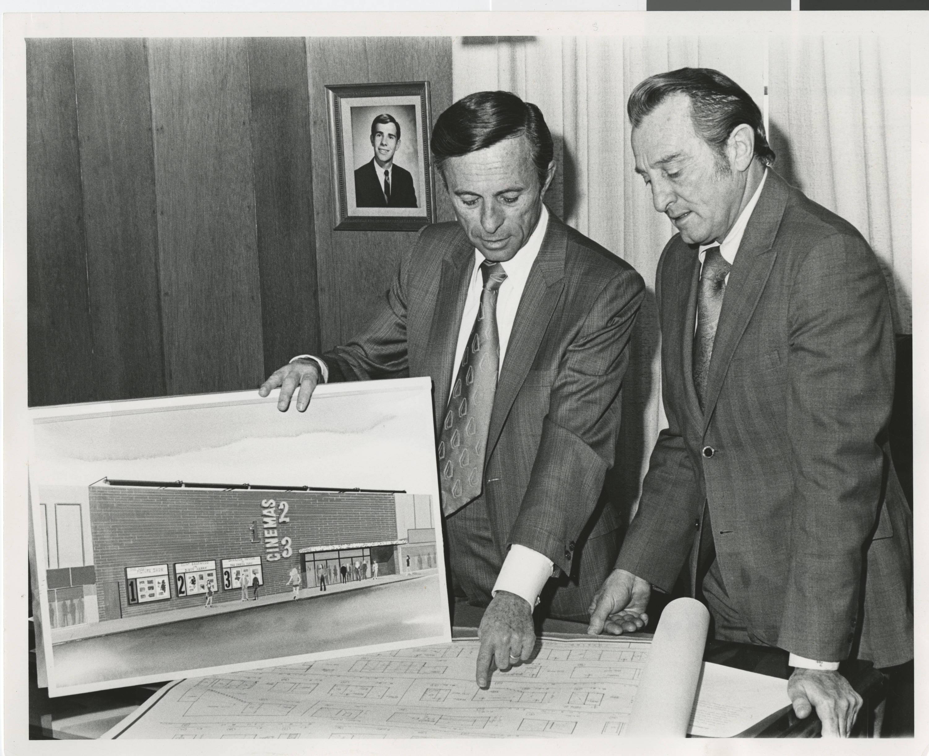 Photograph of Lloyd Katz and unknown man with rendering and blue prints for Cinemas 1, 2, 3